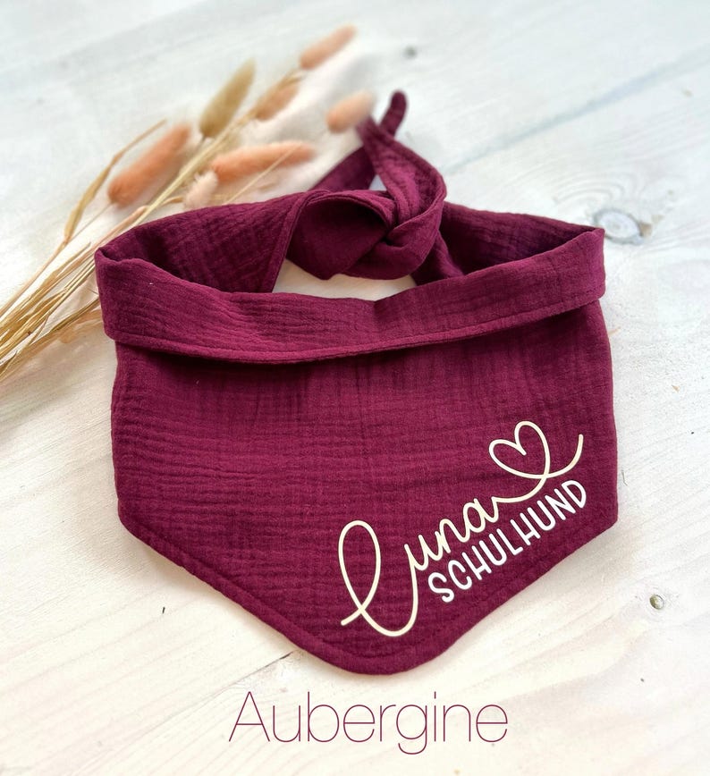 May include: A burgundy bandana with the text "Luna Schulhund" in white with a heart symbol. The bandana is made of a soft, textured fabric.
