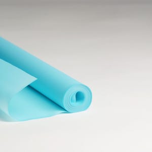 May include: A roll of light blue wrapping paper is partially unrolled, showing the smooth, slightly translucent texture of the paper.