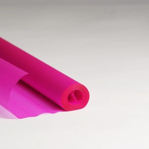May include: A roll of bright pink tissue paper, unfurling to reveal the soft, translucent material.