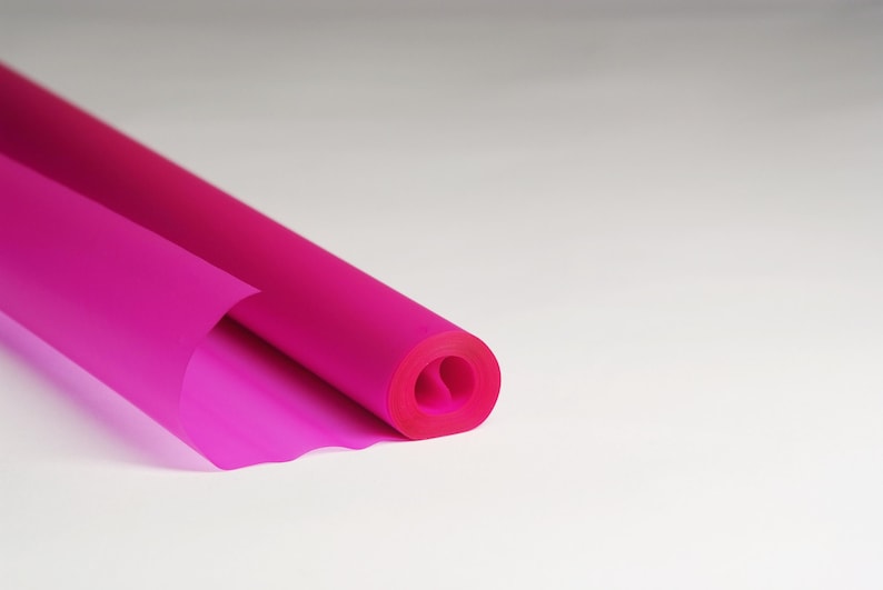 May include: A roll of bright pink tissue paper, unfurling to reveal the soft, translucent material.