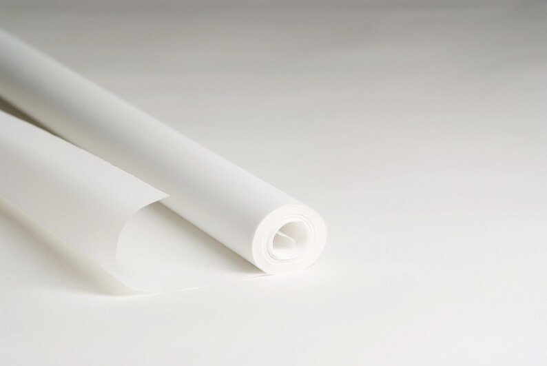 May include: A roll of white paper is partially unrolled, revealing the smooth, white surface of the paper.