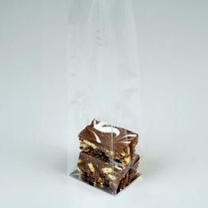 May include: Two chocolate and biscuit squares stacked on top of each other in a clear plastic bag. The chocolate is swirled with white and the biscuit is visible on the bottom layer.