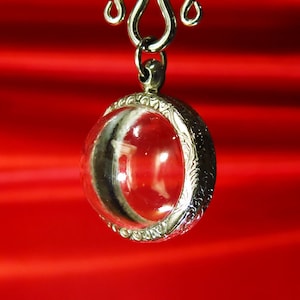 Op de afbeelding: Een zilveren ketting met een hanger van helder glas. De hanger heeft een zilveren filigraanrand.