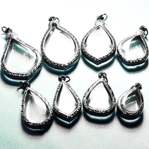 Può includere: Otto ciondoli d'argento con inserti in vetro trasparente. I ciondoli hanno la forma di una lacrima e presentano disegni intricati.