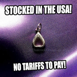 May include: A silver-toned pendant with a teardrop-shaped glass or crystal center, set against a textured purple background. The text "STOCKED IN THE USA!" and "NO TARIFFS TO PAY!" are displayed in white.