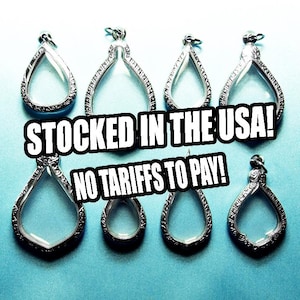 May include: An assortment of silver-toned, teardrop-shaped pendants with ornate detailing. The pendants have a clear, glass-like center. The text "STOCKED IN THE USA! NO TARIFFS TO PAY!" is overlaid on the image.