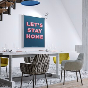 Puede incluir: Un comedor con una mesa blanca y cuatro sillas. Las sillas est&aacute;n tapizadas con diferentes telas, incluyendo un patr&oacute;n de chevron blanco y negro y una tela gris. Un p&oacute;ster enmarcado con el texto "Let's Stay Home" cuelga de la pared.