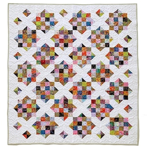 Op de afbeelding: Handgemaakte quilt met kleurrijke sterpatronen op een witte achtergrond. De sterren zijn gemaakt van kleine, kleurrijke stofvierkantjes. De quilt heeft een gewatteerde rand. Afmetingen: ongeveer 150 cm x 150 cm.