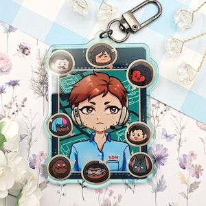 May include: A clear acrylic keychain with a cartoon illustration of a person wearing headphones and the text "SON". The keychain has a silver clasp and includes several small character portraits around the main image.