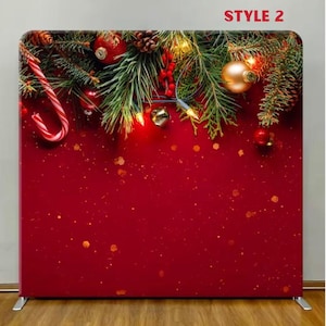May include: A red Christmas backdrop with festive decorations. The top features pine branches, ornaments, candy canes, and string lights. The text "STYLE 2" is displayed at the top. The backdrop is supported by a silver metal frame.