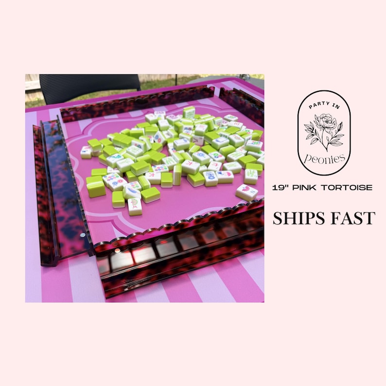 May include: A pink Mahjong table with a tortoise shell border, filled with green and white tiles. The table is 19 inches in size and features the text "Party in Peonies".