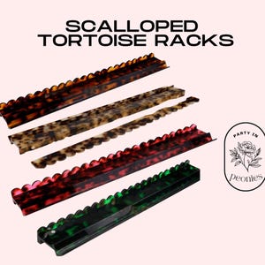 May include: Scalloped tortoise racks in shades of brown, tan, red, and green. The racks feature a scalloped edge and are displayed against a light pink backdrop. The text "SCALLOPED TORTOISE RACKS" is at the top.