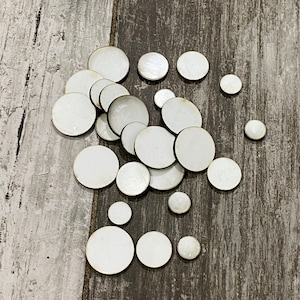Pode incluir: Uma coleção de discos de madeira brancos e circulares de vários tamanhos. Os discos têm uma superfície lisa e em branco e estão dispostos sobre um fundo de madeira envelhecida cinza e castanho. Adequados para artesanato e projetos DIY.