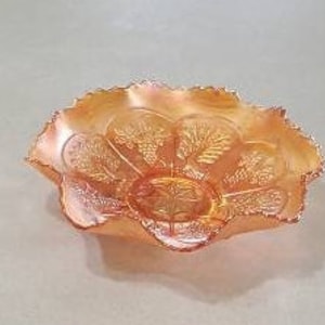 Puede incluir: Un cuenco vintage de vidrio ámbar con un borde festoneado y un diseño floral. El cuenco tiene un aspecto delicado y femenino y sería perfecto para servir aperitivos o postres.