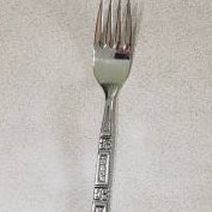 May include: A silver fork with a decorative pattern on the handle.