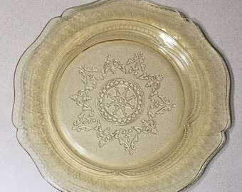 May include: A vintage yellow glass plate with a scalloped edge and a delicate floral design in the center.