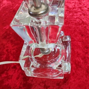 May include: A clear glass lamp base with a square shape and a geometric design. The base is made of multiple layers of glass, creating a unique and intricate look.