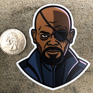 May include: A sticker featuring a stylized illustration of a bald man with an eyepatch and a goatee. The sticker is next to a U.S. quarter for size comparison. The man's skin is brown, and he wears a black eyepatch and a dark blue jacket.