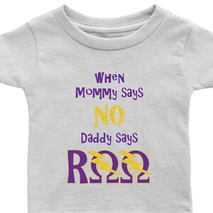 Könnte beinhalten: Ein weißes Baby-T-Shirt mit dem Text "When Mommy Says No Daddy Says R22" in lila und goldenen Glitzerbuchstaben.