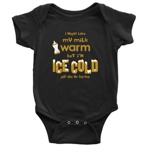 May include: Black baby onesie with gold text that reads "i Might Like my milk warm but I'M ICE COLD just like My Pop-Pop". The onesie has a picture of a baby bottle with milk in it.