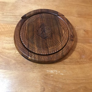 Puede incluir: Un bol de fruta redondo de madera extensible con un dise&ntilde;o floral tallado. El bol est&aacute; hecho de madera marr&oacute;n oscura y tiene un acabado natural.