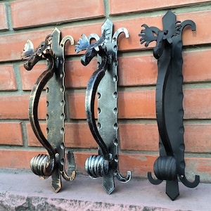 Puede incluir: Tres tiradores de puerta decorativos con diseños de cabeza de alce. Los tiradores están hechos de metal y tienen un acabado negro, plateado y dorado.