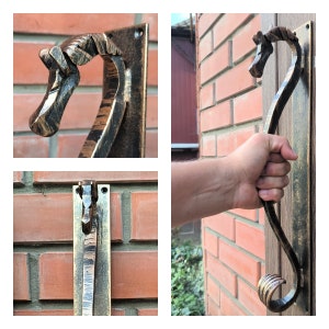 May include: A black and gold metal door handle shaped like a horse's head. The handle is mounted on a brick wall.