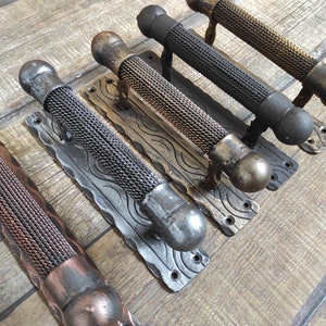 Op de afbeelding: Vier decoratieve deurgrepen met een zwarte metalen basis en een draadgaasontwerp. De grepen zijn in verschillende afwerkingen verkrijgbaar, waaronder koper, zwart en goud.