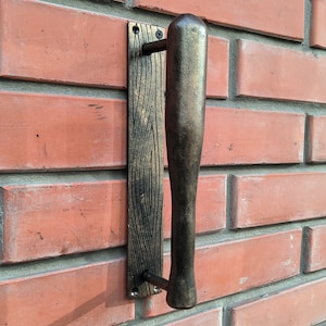 May include: A black metal door handle with a long, rectangular handle and a decorative backplate with a woodgrain pattern.