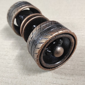 May include: A set of four black and gold metal rings with a tyre tread pattern. The rings are stacked on top of each other.