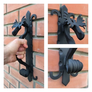 Puede incluir: Pomo de puerta de metal negro con un diseño de cabeza de alce. El pomo está fijado a una pared de ladrillo.