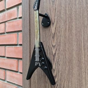 Op de afbeelding: Zwarte deurknop in de vorm van een elektrische gitaar met een houtnerfdesign op het lichaam.
