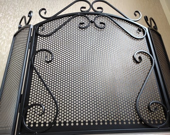 Puede incluir: Pantalla de chimenea de metal negro con un diseño decorativo de desplazamiento y un panel de malla. La pantalla está hecha de tres secciones que se pueden plegar para su almacenamiento.