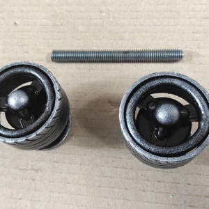 May include: Two black metal drawer pulls with a tyre tread design and a silver finish. The pulls are shown with a silver metal screw.