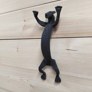 May include: Black metal door handle shaped like a stylized panther with its paws raised in the air.