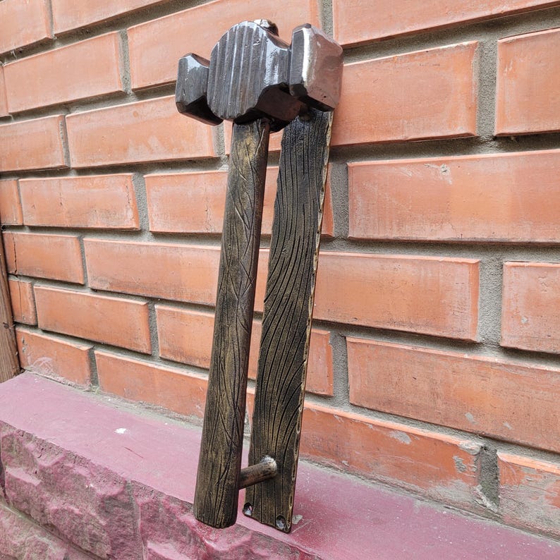 Puede incluir: Un juego de manijas de puerta decorativas con dise&ntilde;o de martillo. La manija es de madera marr&oacute;n oscuro con un acabado texturizado y detalles dorados. La cabeza del martillo es de un tono marr&oacute;n m&aacute;s oscuro.