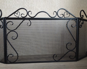 Puede incluir: Pantalla de chimenea de metal negro con un diseño decorativo de desplazamiento y un panel de malla. La pantalla está hecha de tres secciones que se pliegan juntas.