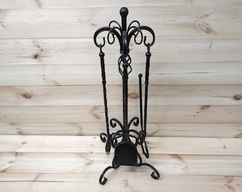May include: Black metal fireplace tool set with a stand. The set includes a poker, shovel, and tongs. The stand has a decorative scroll design.