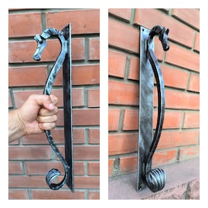May include: A silver door handle with a decorative horse head design. The handle is mounted on a brick wall.