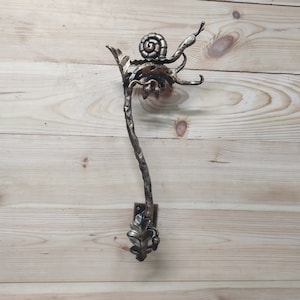 May include: A metal coat hook shaped like a branch with a snail and leaf design. The hook is painted in a gold and brown finish.
