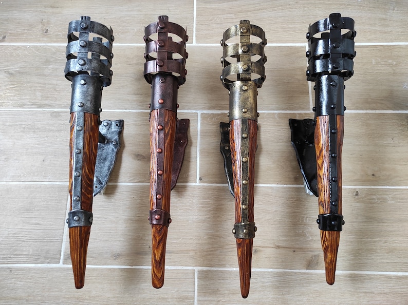May include: Four wall-mounted torch sconces with a rustic wood and metal design. Each sconce has a different metal finish: silver, copper, gold, and black.