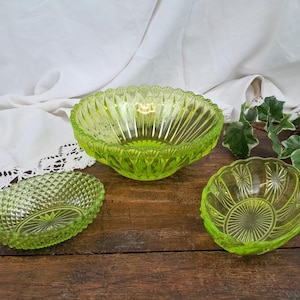 May include: Three green glass bowls of varying sizes and patterns. The largest bowl has a fluted design, the medium bowl has a diamond pattern, and the smallest bowl has a circular pattern.