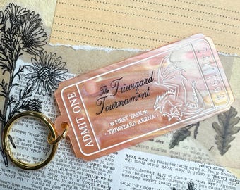May include: A peach-colored ticket with a white outline of a dragon and the text "The Triwizard Tournament *FIRST TASK* *TRIWIZARD ARENA*" printed on it. The ticket is labeled "ADMIT ONE" and has the date "24111994" printed on it.