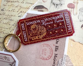May include: A red glitter keychain with a train ticket design. The ticket reads "London to Hogwarts Hogwarts Express" and has a date of "01091991". The keychain has a gold ring.