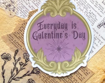 May include: A sticker with a gold-colored ornate frame and a lavender center. The text "Everyday is Galentine's Day" is written in a decorative font. The sticker is placed on a background of aged paper and vintage ephemera.
