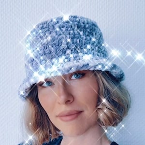 Könnte beinhalten: Ein hellblauer, gehäkelter Bucket-Hut mit flauschiger Textur. Der Hut wird von einer Person mit kurzen blonden Haaren getragen.