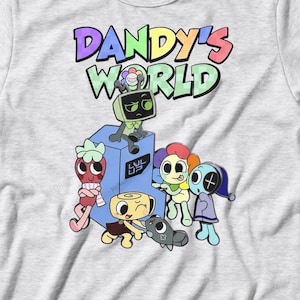 Op de afbeelding: Lichtgrijs t-shirt met de tekst "Dandy's World" in regenboogkleuren boven een cartoonafbeelding. De afbeelding toont verschillende cartoonfiguren en een robot.