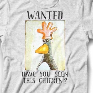 Puede incluir: Una camiseta gris con un cartel de se busca de estilo vintage que presenta un pingüino de dibujos animados con un guante en la cabeza. El cartel dice "WANTED" y "HAVE YOU SEEN THIS CHICKEN?"
