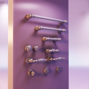 May include: A collection of antique-style door hardware, including handles, knobs, and keyhole covers, in a silver and gold finish. The hardware is displayed against a purple background, showcasing various designs and sizes.