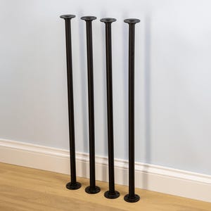 May include: Four black metal table legs with a round top and base. The legs are straight and cylindrical, with a matte finish. The legs are approximately 71 cm tall.